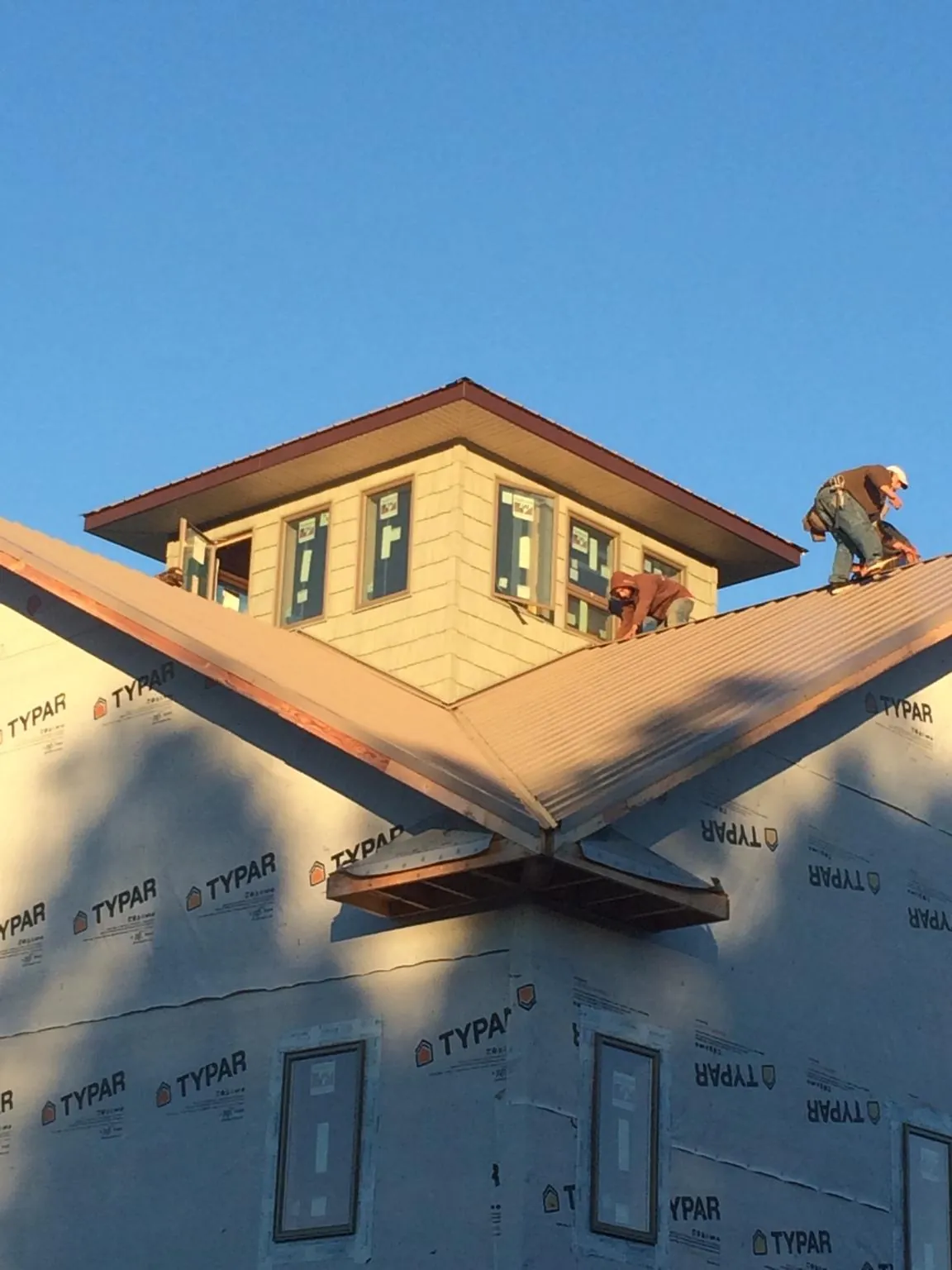 Roofers working around a rooftop cupola on a new metal roof at sunset — Roof Waterproofing in Paradise by Roofing Brothers